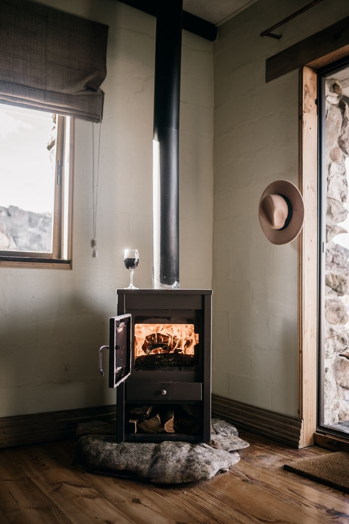 hero-img Warm and inviting modern interior featuring a burning fireplace and glass of wine.